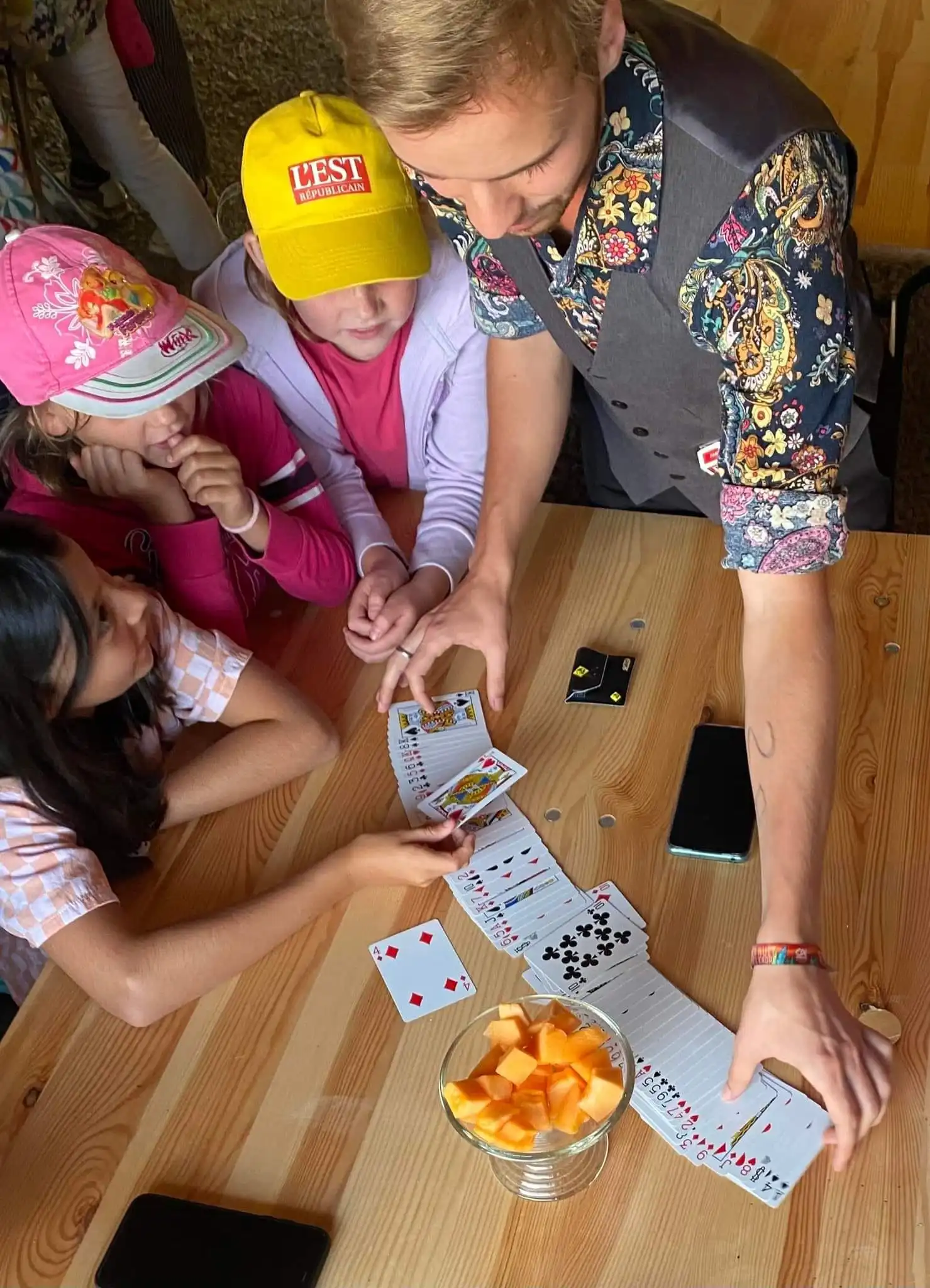 eligius qui fais des tours de magie avec des enfants sur une table
