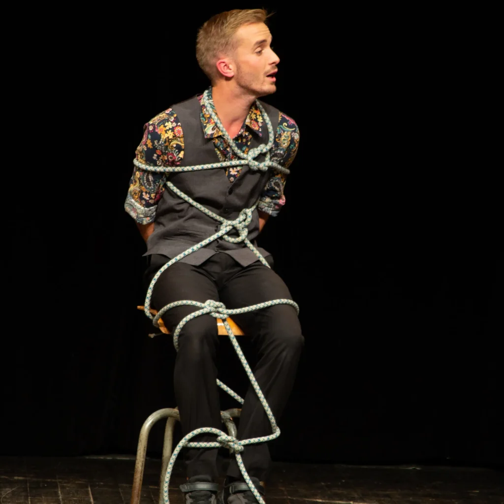 eligius magie durant spectacle en train de se faire attacher avec une corde