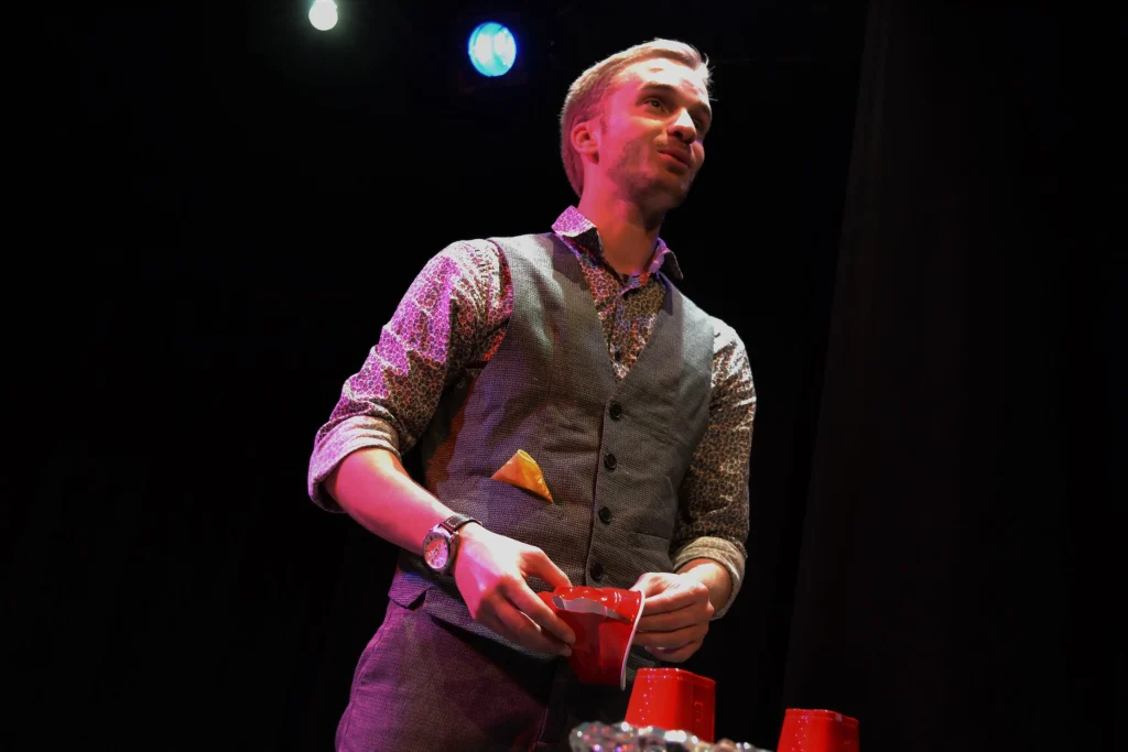eligius debout en spectacle avec des verres en plastique rouge